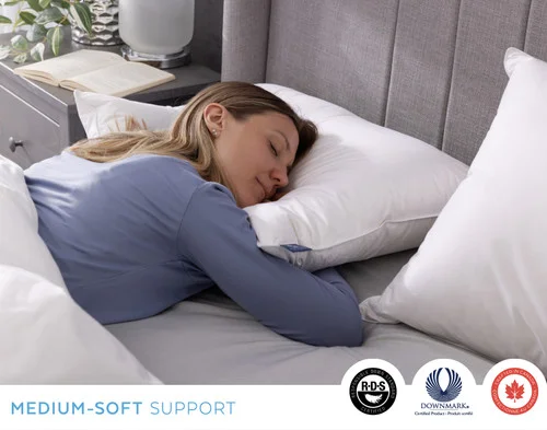 Woman resting on her stomach with her face turned on our Luxurious Down Pillow.