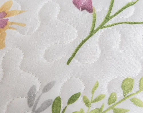 Close-up on the green stem and pink florals on the face pattern of our Meadow Coverlet Set.