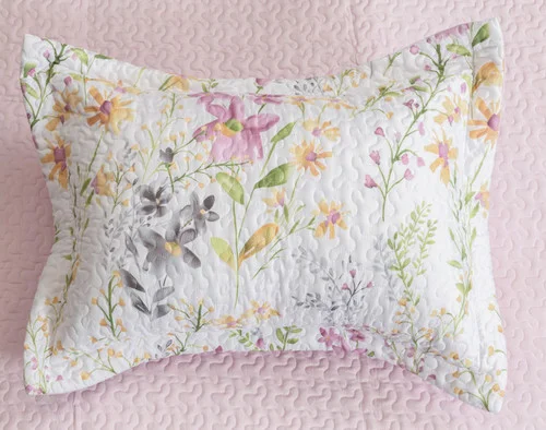 Top view of the pillow sham for our Meadow Coverlet Set sitting over its coordinating coverlet's pink reverse.