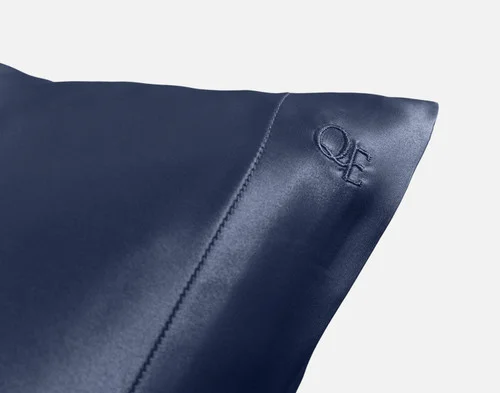 Close-up on the embroidered QE Home logo on the corner of our Mulberry Silk Pillowcase in Navy.