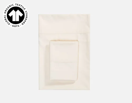 Our Undyed & Unbleached Organic Cotton Sateen Pillowcase folded into a square above the flat sheet from its coordinating sheet set.