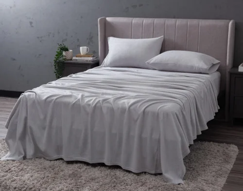 Angled view of our Cuddle Fleece Sheet Set in Granite fitted over a queen bed in a dark grey bedroom.