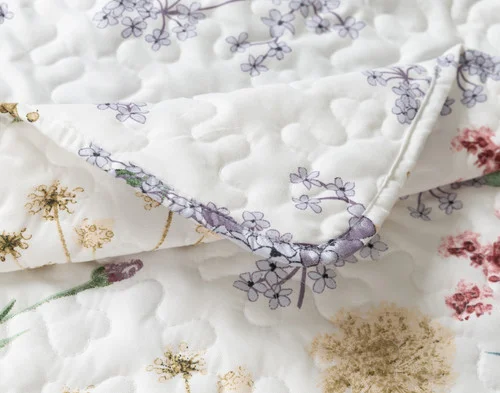 Close up of our Danielle Coverlet Set folded at its corner to reveal its floral main and reverse sides.