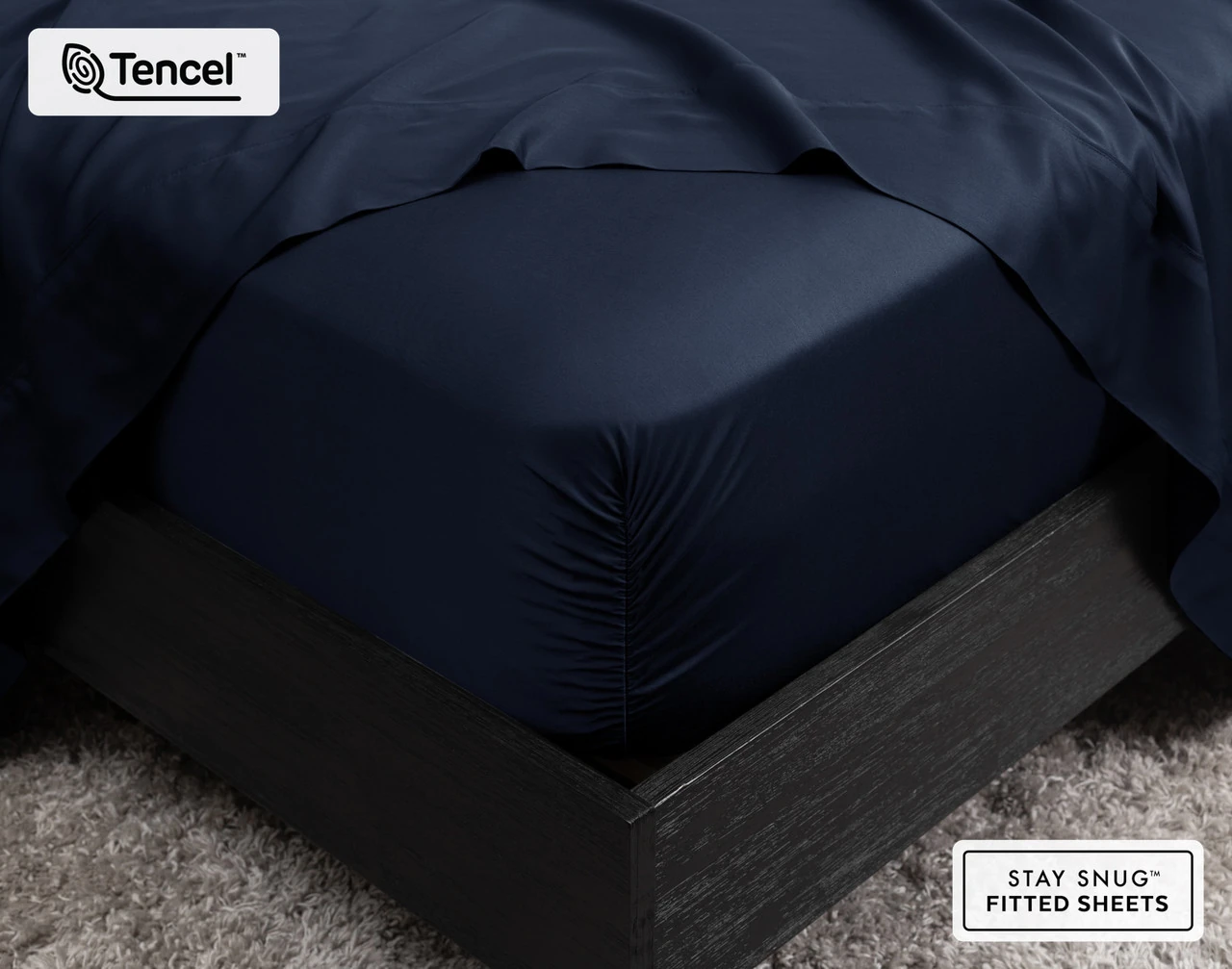 Close-up of the corner on our BeechBliss TENCEL™ Modal Fitted Sheet in Deep Space snugly fit over a mattress with a flat sheet draped on top.