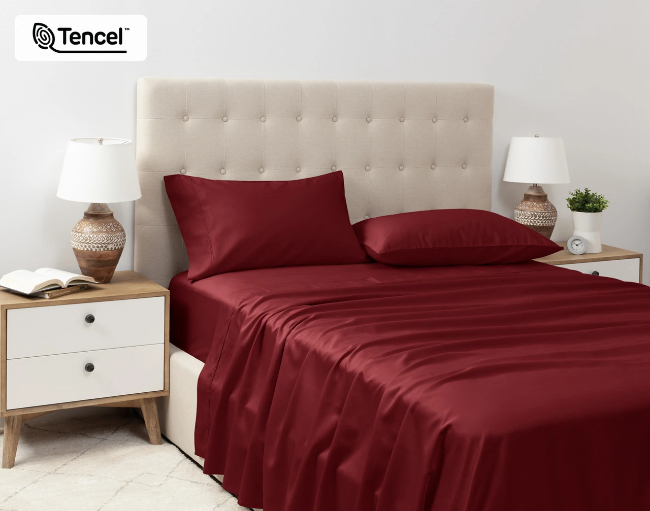 Angled view of our Eucalyptus Luxe TENCEL™ Lyocell Sheet Set in Black Cherry dressed over a queen bed in a tidy white bedroom.