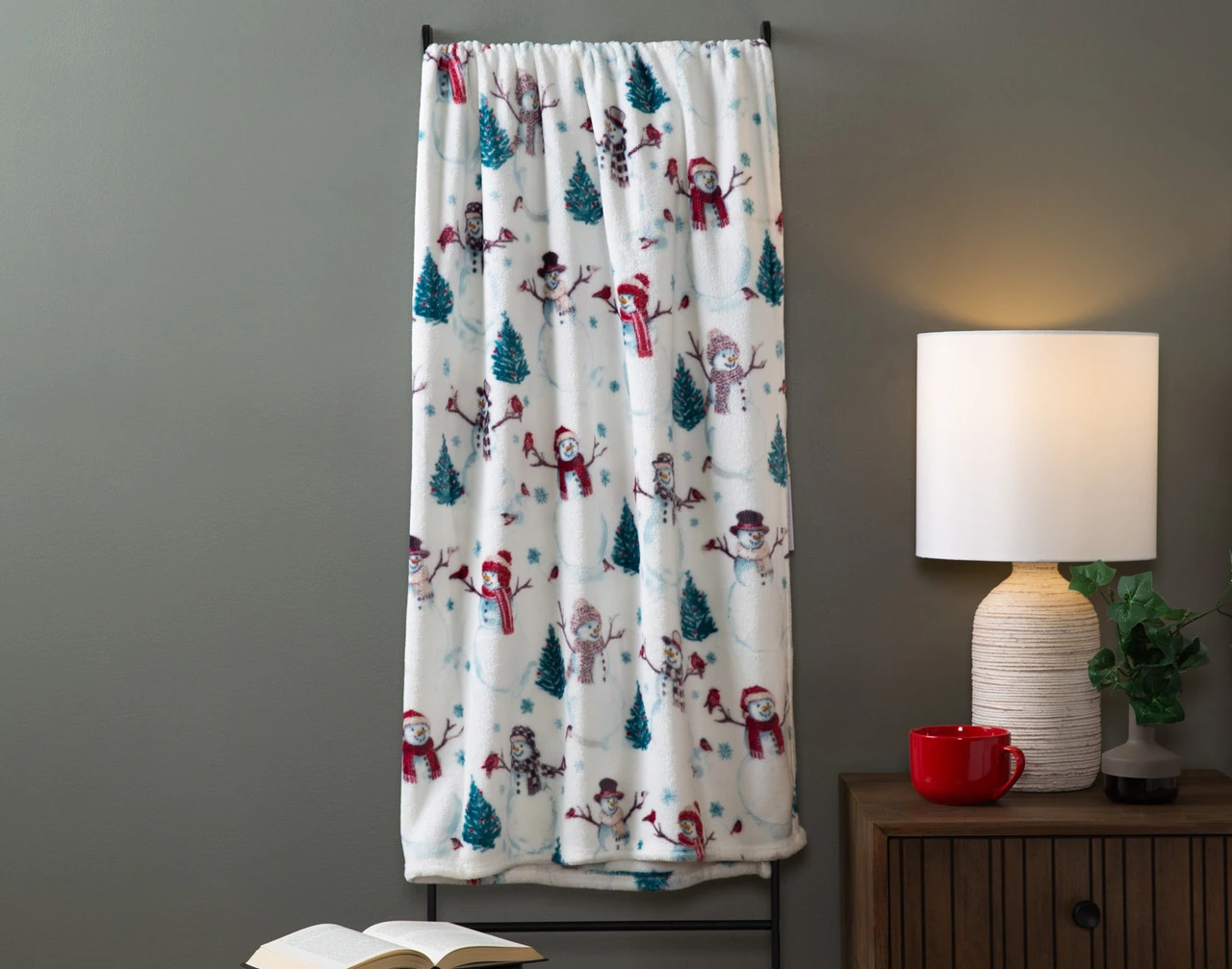Our White Christmas Holiday Fleece Throw draped over a hanger in a neutral living room.