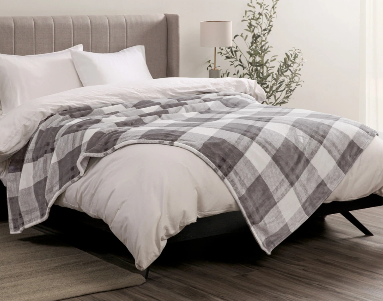 Our Plaid Cashmere Touch Fleece Blanket in Slate draped over a bed.