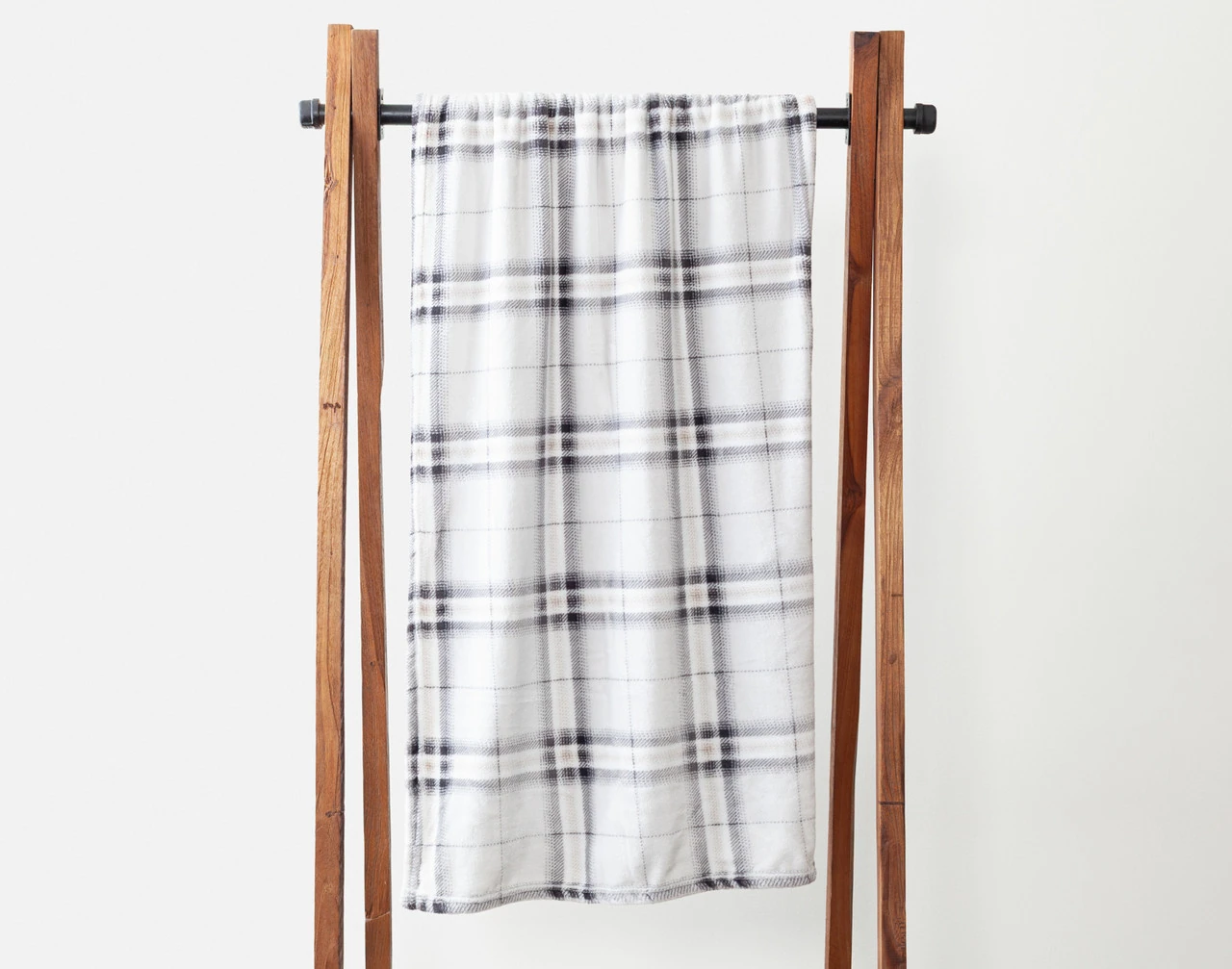 Our Strathmore Plaid Fleece Throw draped over a wooden hanger.