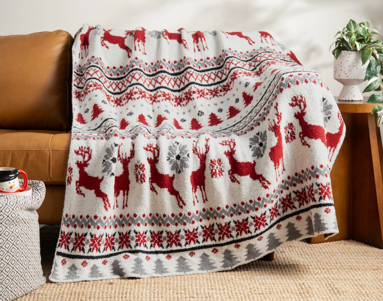 Our Nordic Noel Chenille Jacquard Throw draped over a brown couch.