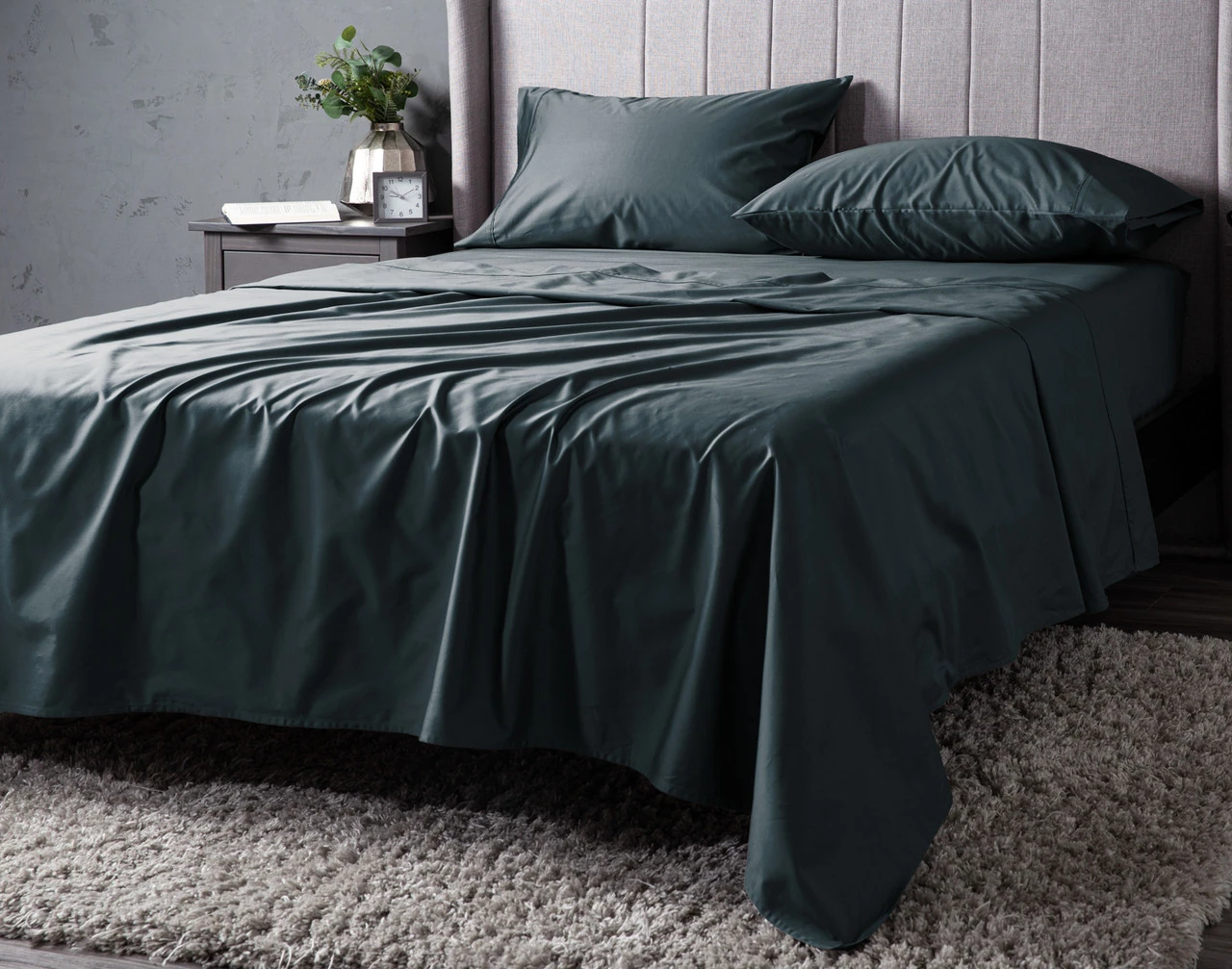 Angled view of our Teal Cove Dream Sateen Sheet Set dressed over a plain queen bed.