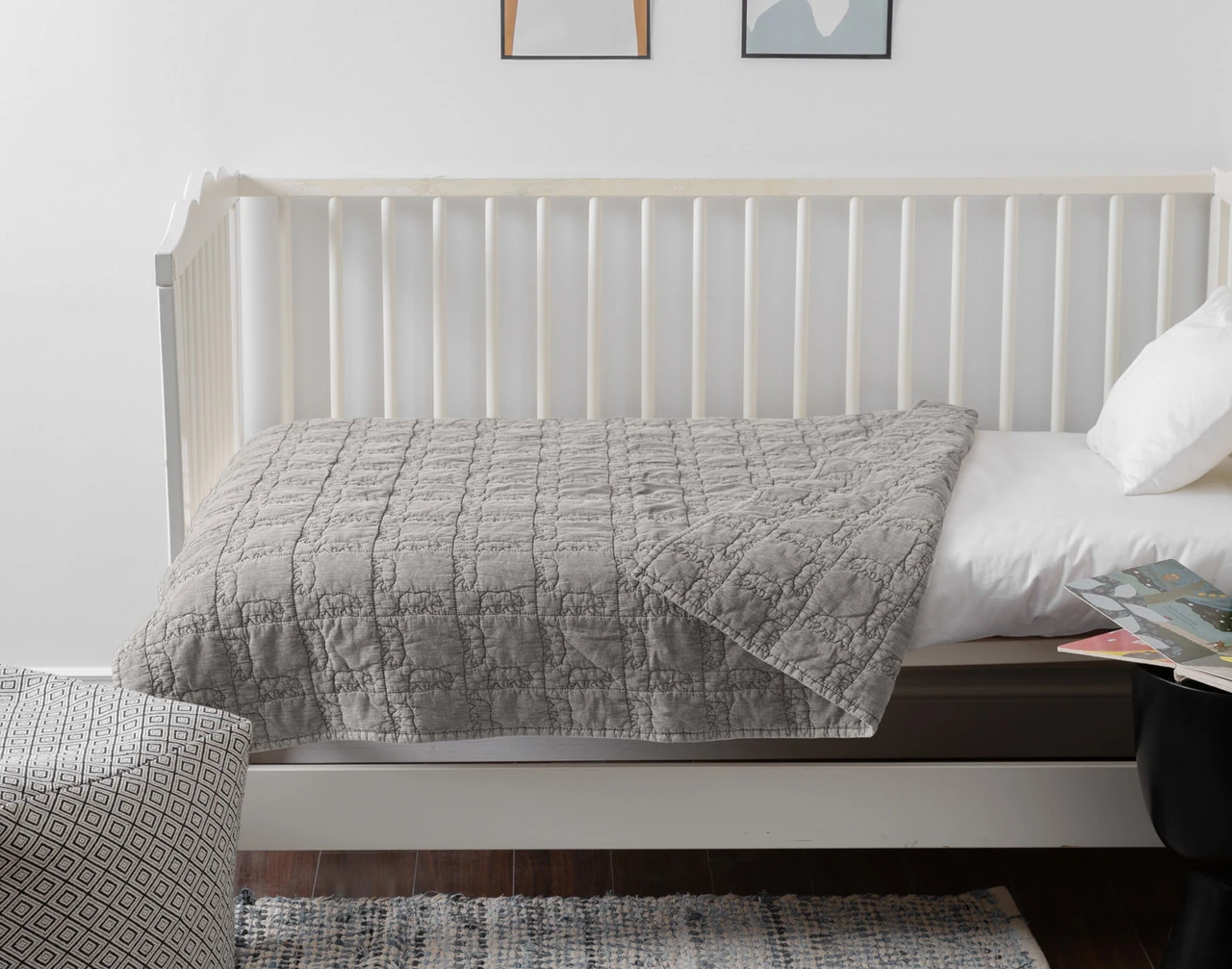 Side view of our Bear Crossing Crib-Sized Quilt dressed over a white crib mattress.