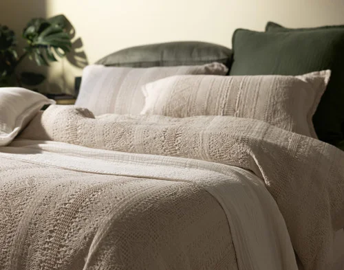 Angled view of our Rustico collections dressing a bed with green sheeting.