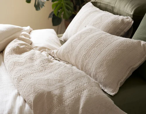 Our Rustico Pillow Shams dressing the head of a bed with our Rustico collection and green accessories.