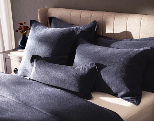 Angled view of our Deep Dive pillow shams and cushion covers resting against a headboard.