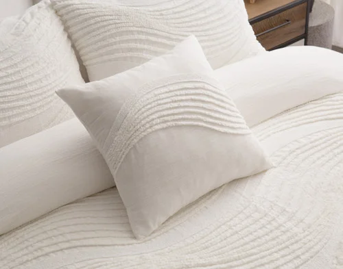 Angled view of our Savary Square Cushion Cover dressing the head of a bed with our Savary collection.