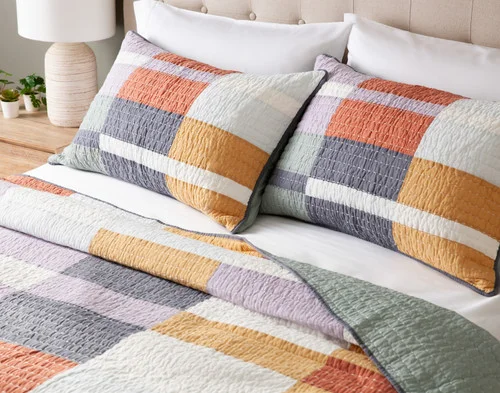 Close up on the head of a bed dressed in our Domino Quilt Set.