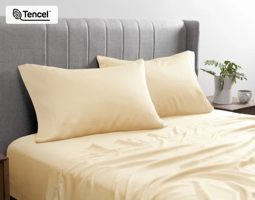Angled view of the pillowcases from our BeechBliss TENCEL™ Modal Sheet Set in Cornsilk resting against a headboard.