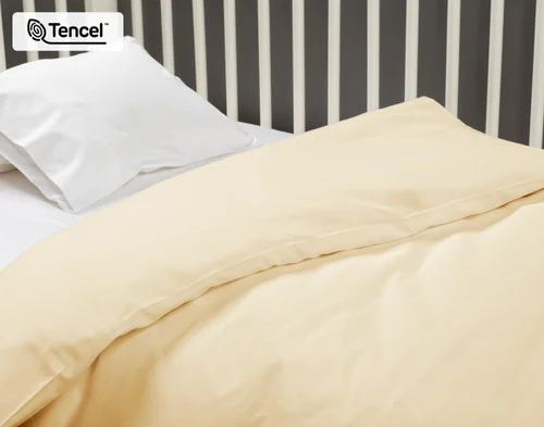 Close-up view of our Cornsilk BeechBliss TENCEL™ Modal Crib-Sized Duvet Cover dressed over a small white crib.