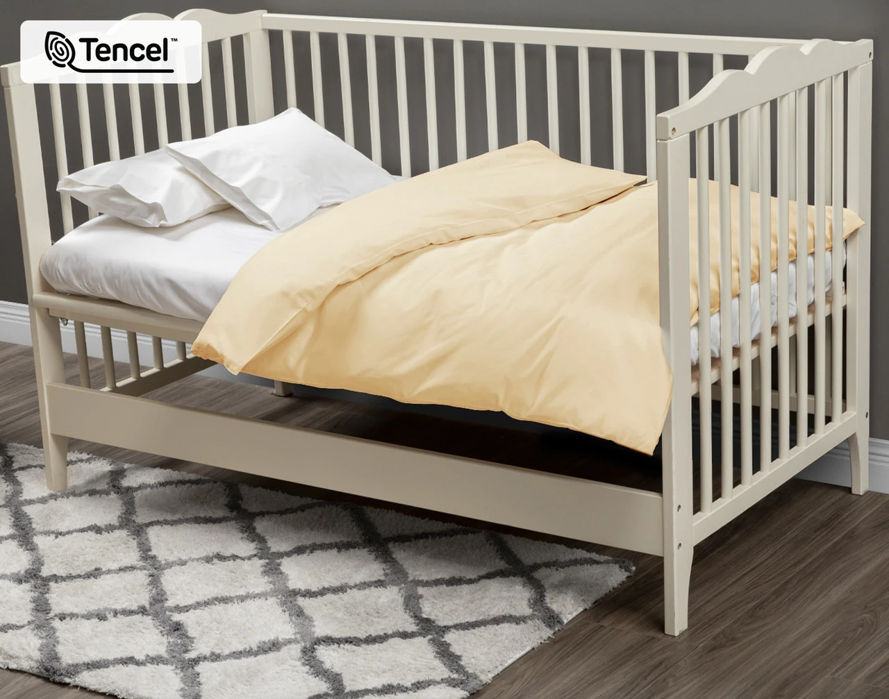 Angled view of our Cornsilk BeechBliss TENCEL™ Modal Crib-Sized Duvet Cover dressed over a small white crib.