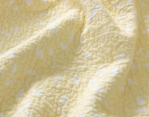 Reverse view of the yellow backing with silhouetted white branches on our Florian Quilt Set.