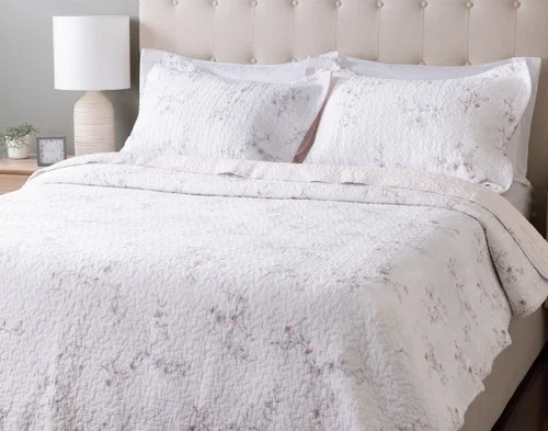Angled view of our Blossom Cotton Quilt Set dressed over an empty queen bed.