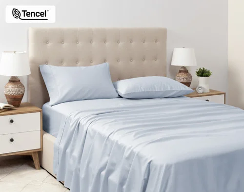 Angled view of our Eucalyptus Luxe TENCEL™ Lyocell Sheet Set in Blue Chalk dressed over a queen bed in a tidy white bedroom.