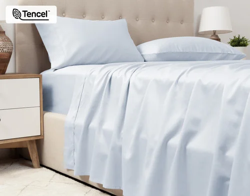 Lower view of our Eucalyptus Luxe TENCEL™ Lyocell Sheet Set in Blue Chalk to show its flat sheet draped over the side of a queen bed.