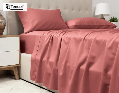 Lower view of our Eucalyptus Luxe TENCEL™ Lyocell Sheet Set in Raspberry Ice to show its flat sheet draped over the side of a queen bed.