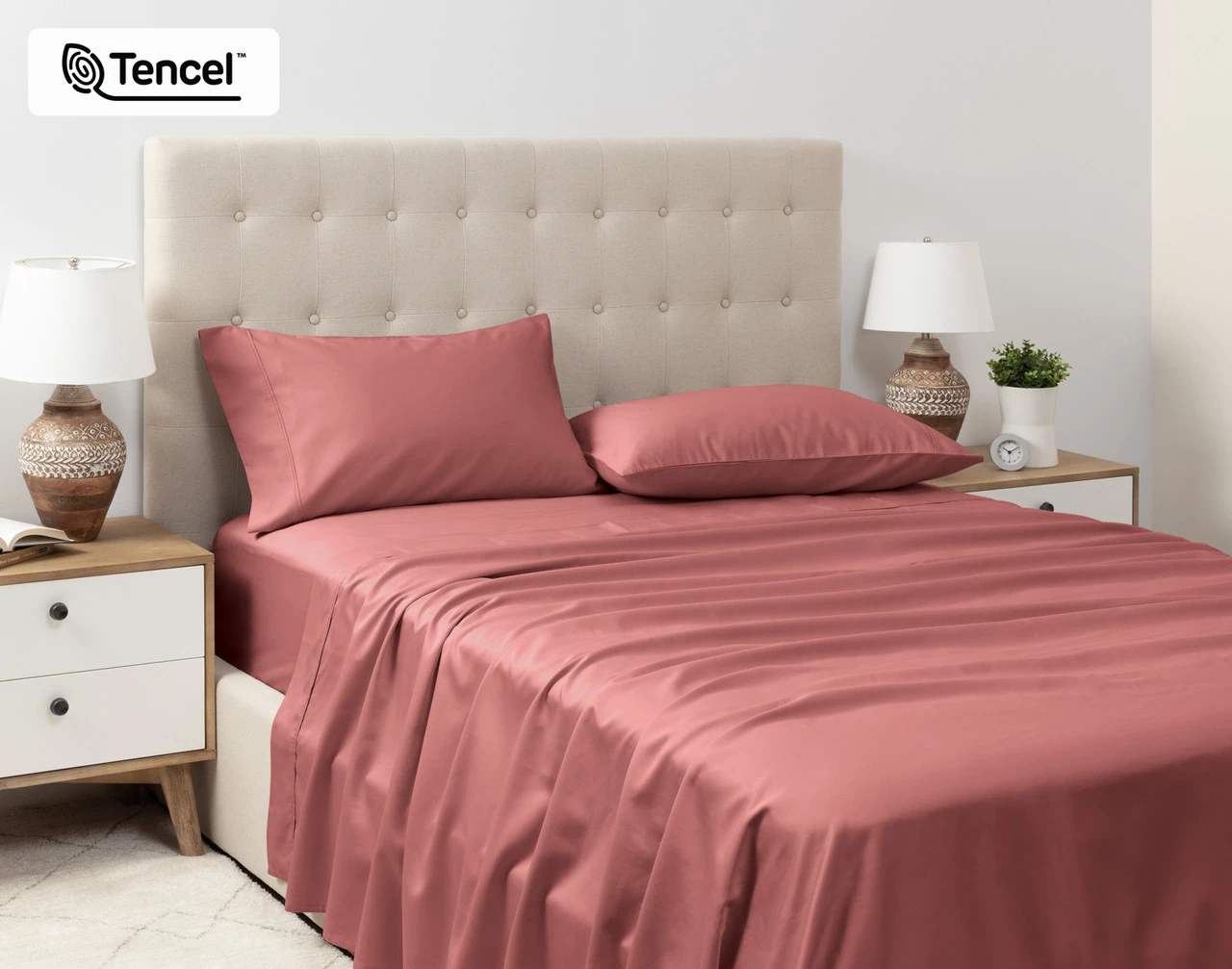 Angled view of our Eucalyptus Luxe TENCEL™ Lyocell Sheet Set in Raspberry Ice dressed over a queen bed in a tidy white bedroom.