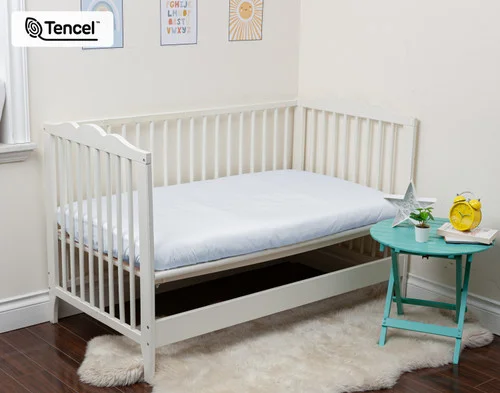 Angled view of a crib mattress dressed in our Blue Chalk Eucalyptus Luxe Crib-Sized Fitted Sheet.