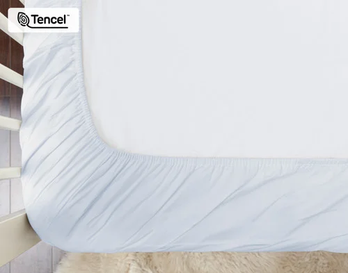 Reverse view of a crib mattress dressed in our Blue Chalk Eucalyptus Luxe Crib-Sized Fitted Sheet to show its standard elastics border.