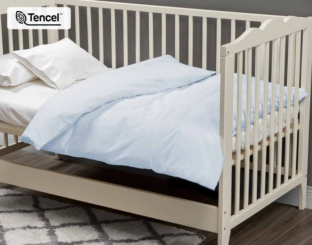 Angled view of our Crib-Sized Eucalyptus Luxe Duvet Cover in Blue Chalk dressed over a crib.