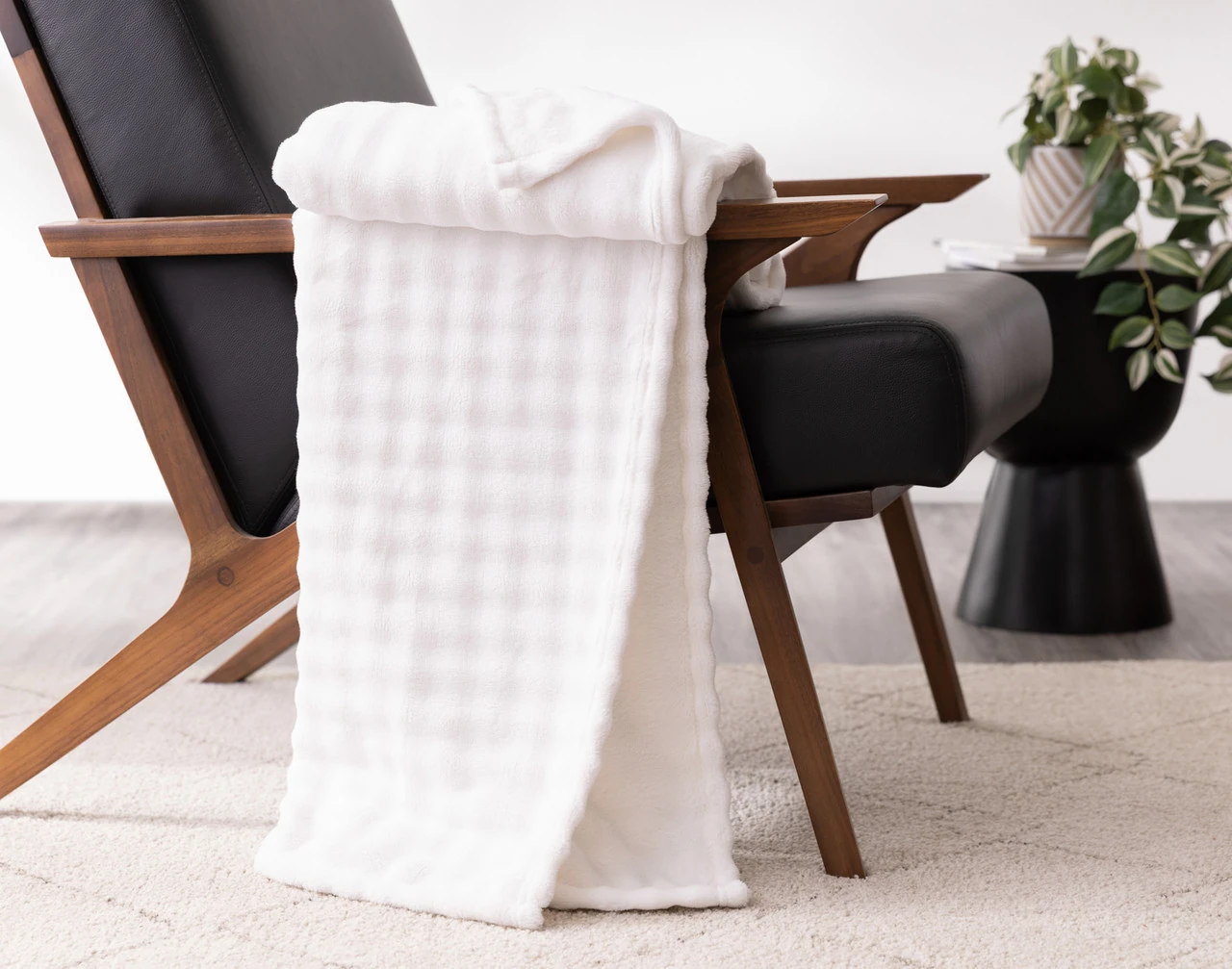 Our White Bubble Breeze Throw draped over the arm of a black chair.