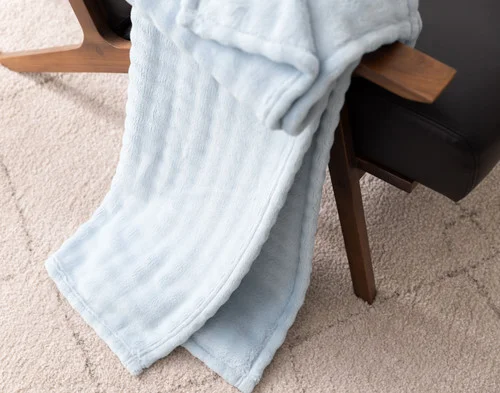 Our Powder Blue Bubble Breeze Throw draped over the arm of a black chair.