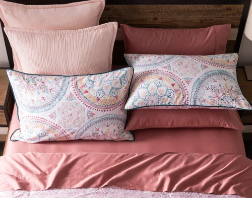 Top-down view of our Mandira Duvet Cover Set dressing a queen bed with pink accessories.