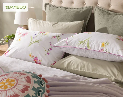 Angled view of our Delicata collection dressing the head of a bed with green accessories.