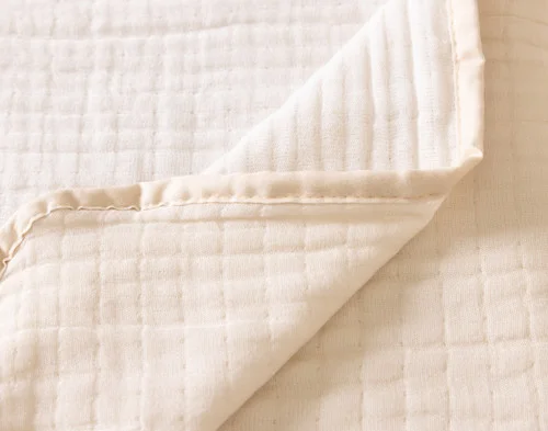 Close up on the folded surface of our Bamboo Gauze Throw in Bone.