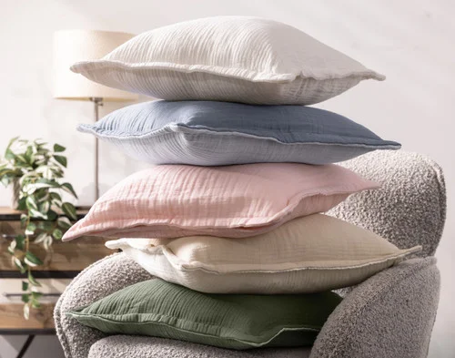 A stack of our Bamboo Gauze Square Cushion Covers on a grey chair.