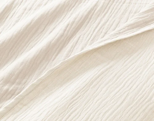 Close-up of our White Bamboo Gauze Blanket to show its surface and off-colour reverse side-by-side.