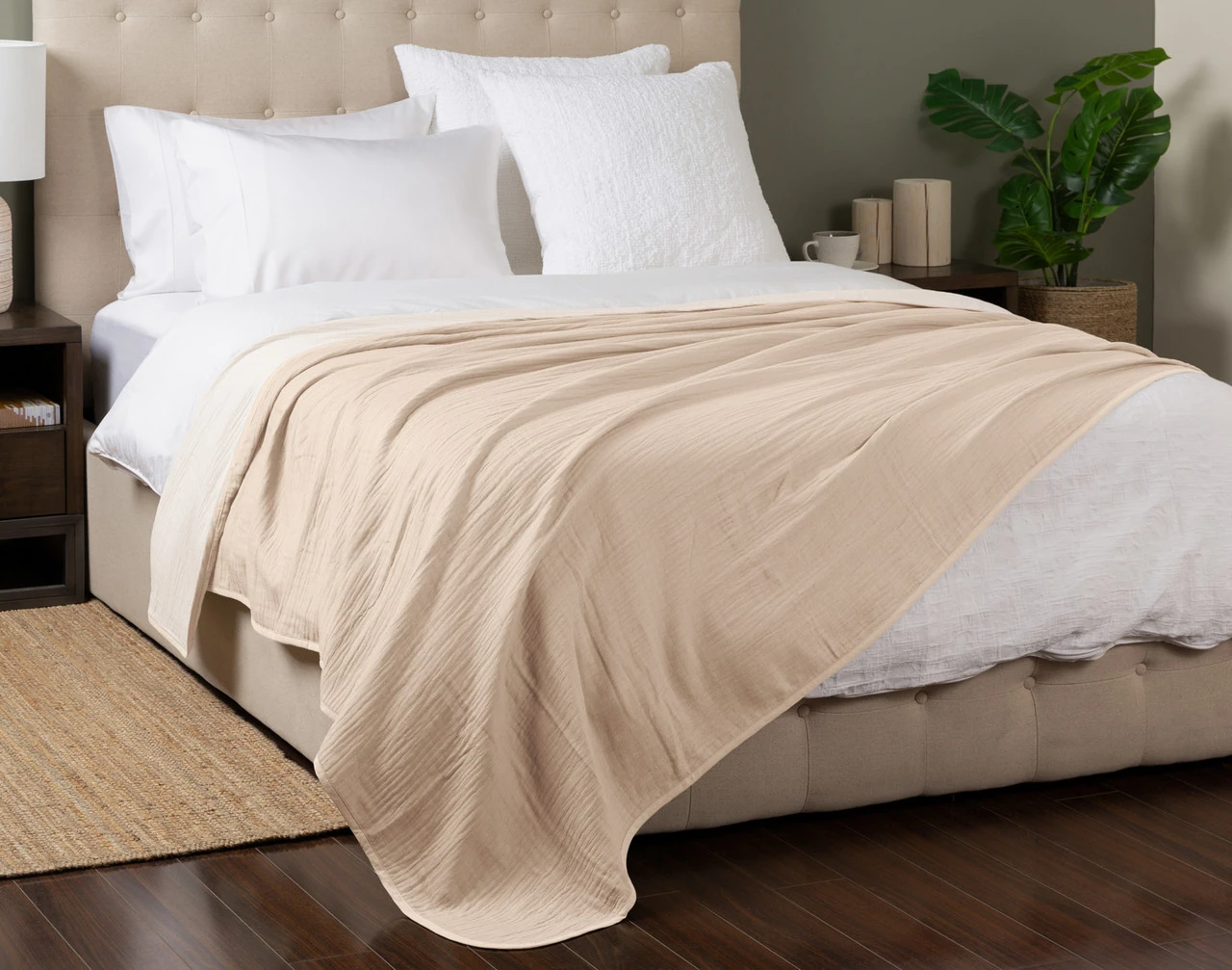 Angled view of our Bone Bamboo Gauze Blanket spread over a white queen-size bed.