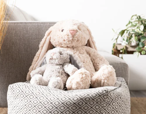 Our large and small Large Easter Plush Bunny Cushions sitting together on a stool.