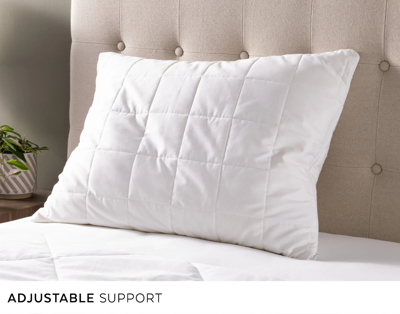 Our PureRest Pillow leaning against the headboard of an empty bed.