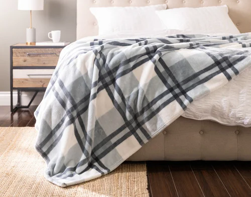 Front view of our Coastline Plaid Blanket draped over a white bed.
