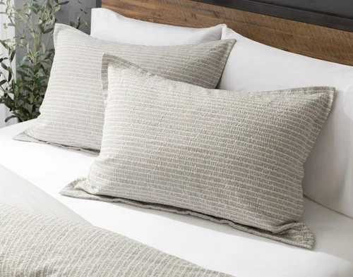 Angled view of our Estrada Pillow Shams resting against a headboard.