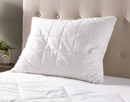 A pillow with our PureRest Wool Filled Pillow Protector resting on a plain white bed.