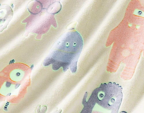 Close-up on the etched designs on our Snuggle Monsters Glow In The Dark Throw with outlines to show its glowing spots.