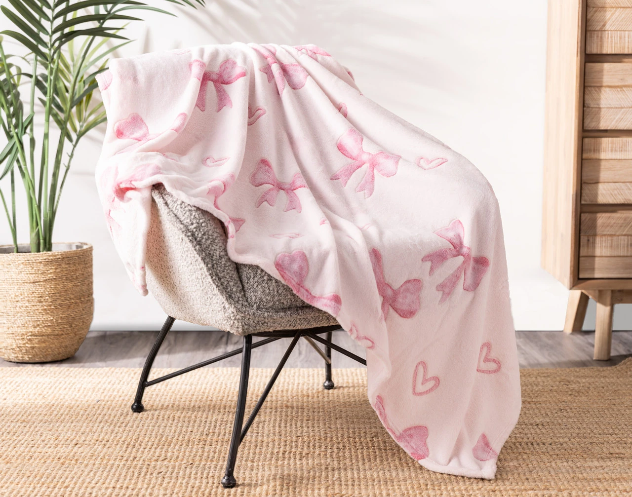 Angled view of our Bows & Hearts Glow In The Dark Throw draped over a chair.
