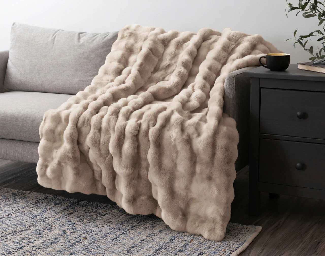 Our Bubble Faux Fur Throw in Champagne draped over a grey couch.