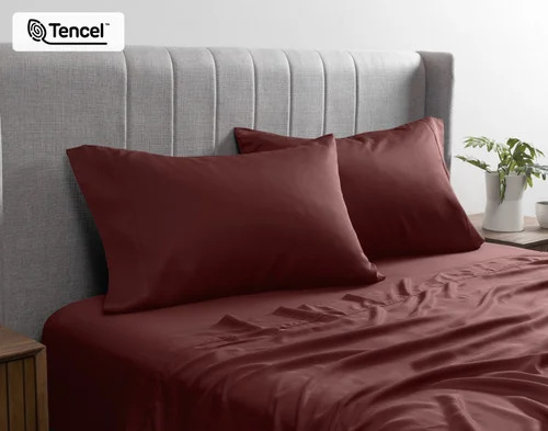 Front view of our BeechBliss TENCEL™ Modal Pillowcases in Mahogany resting against a headboard in a bed with matching sheets.