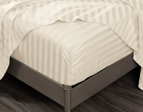 Close-up on the fitted sheet of our Cream Luxor Egyptian Cotton Sheet Set over a mattress, with a matching flat sheet draped overtop.